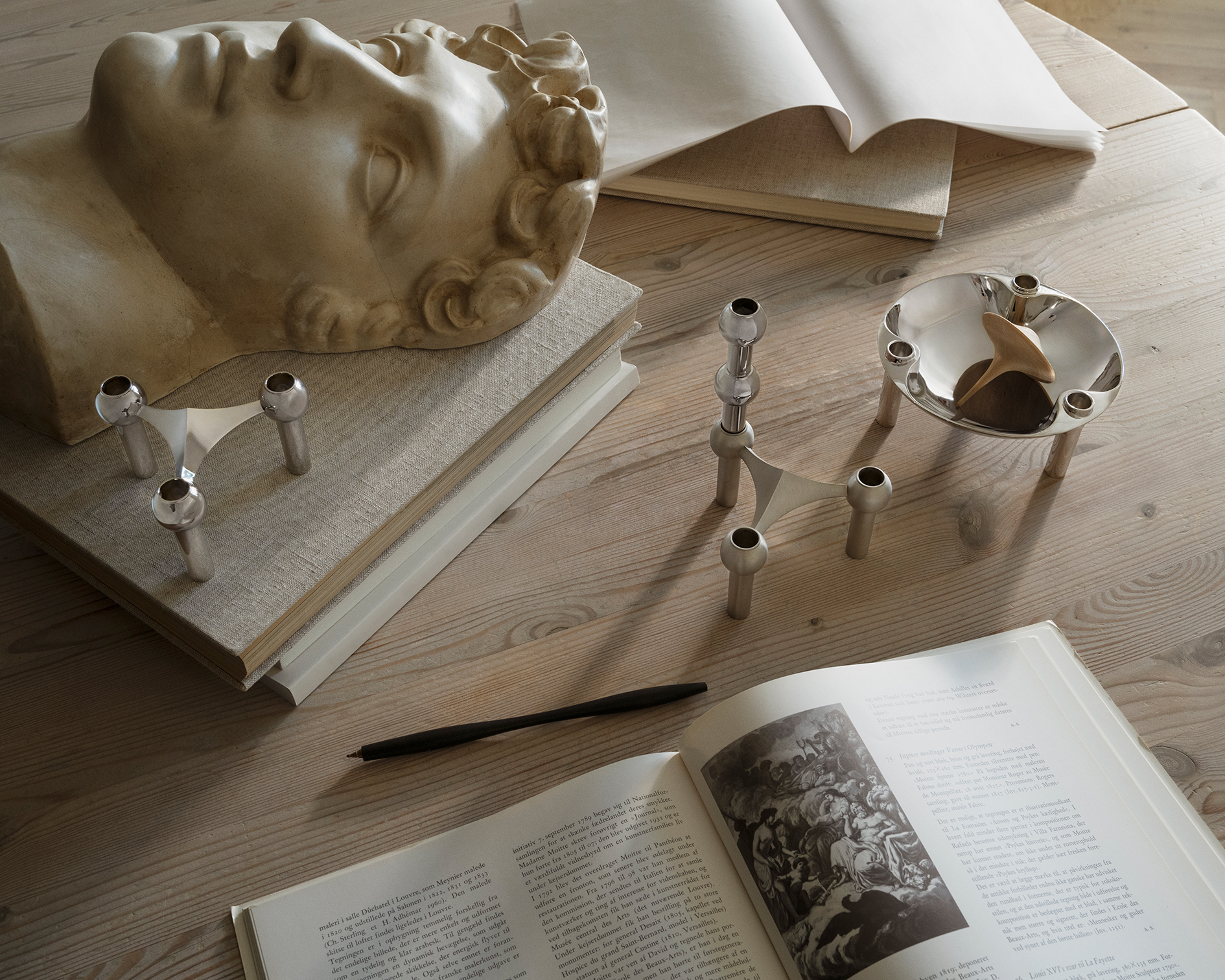 nagel candle holders, bowl and vase in chrome and brushed chrome arranged on a table.