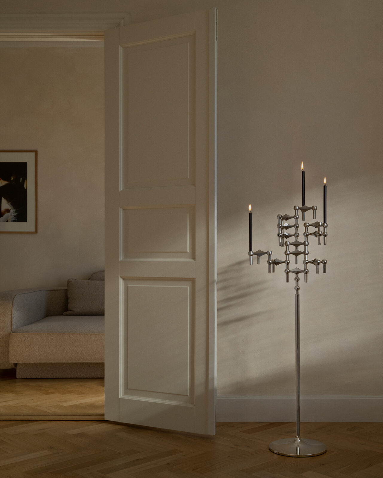 stoff nagel floor stand with nagel candle holders and lit taper candles in a homey setting.