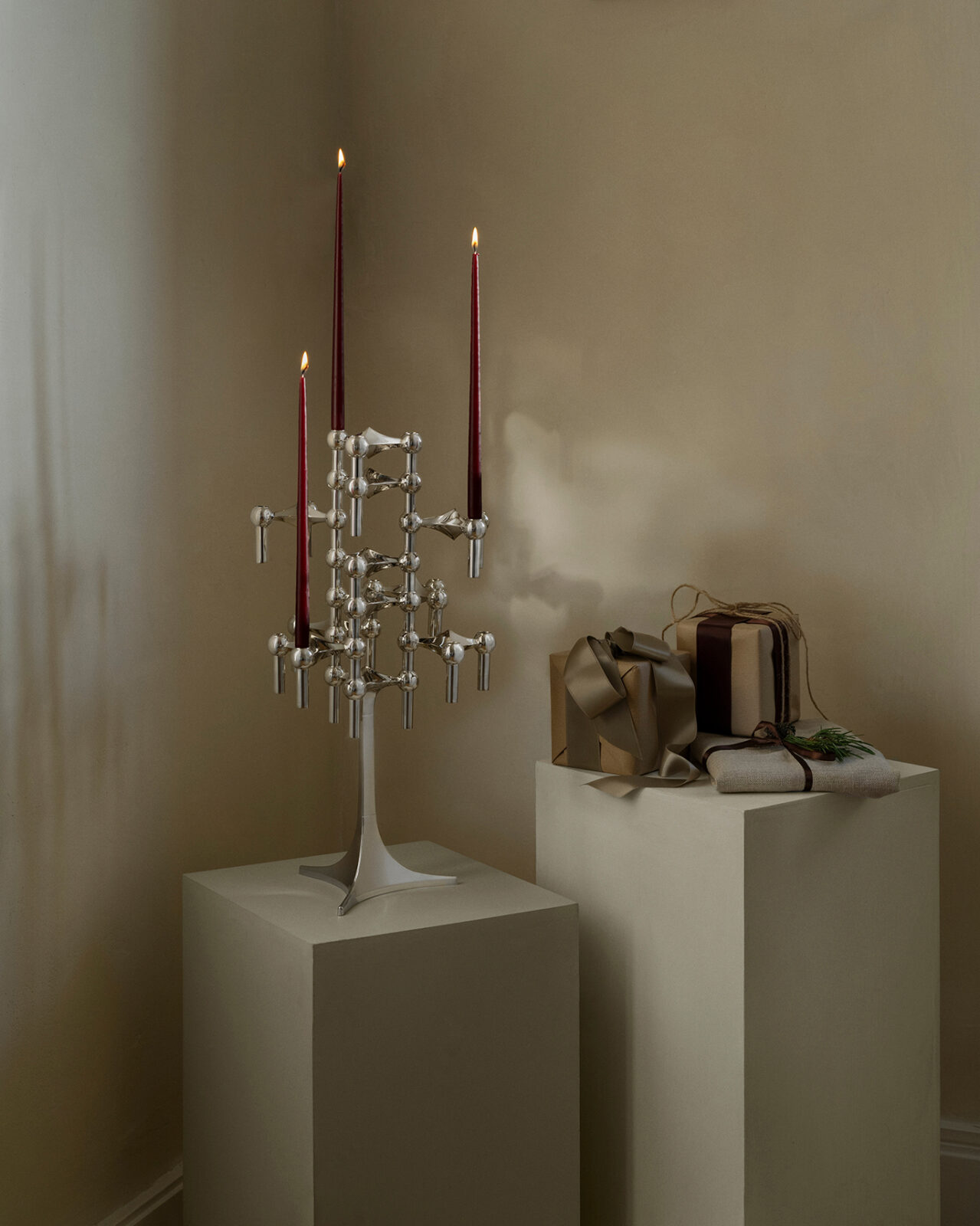 stoff nagel stand in chrome with the nagel candle holders in a sculptural formation and lit candles shown in a christmas setting