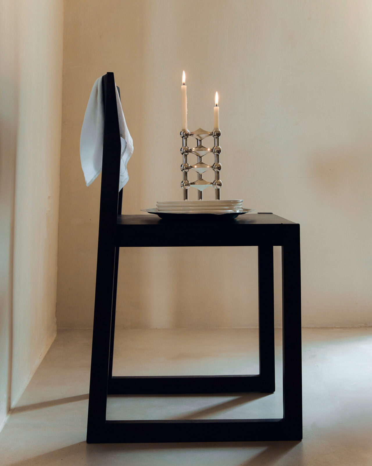 stoff nagel candle holders in chrome stacked on a chair ready to be cleaned