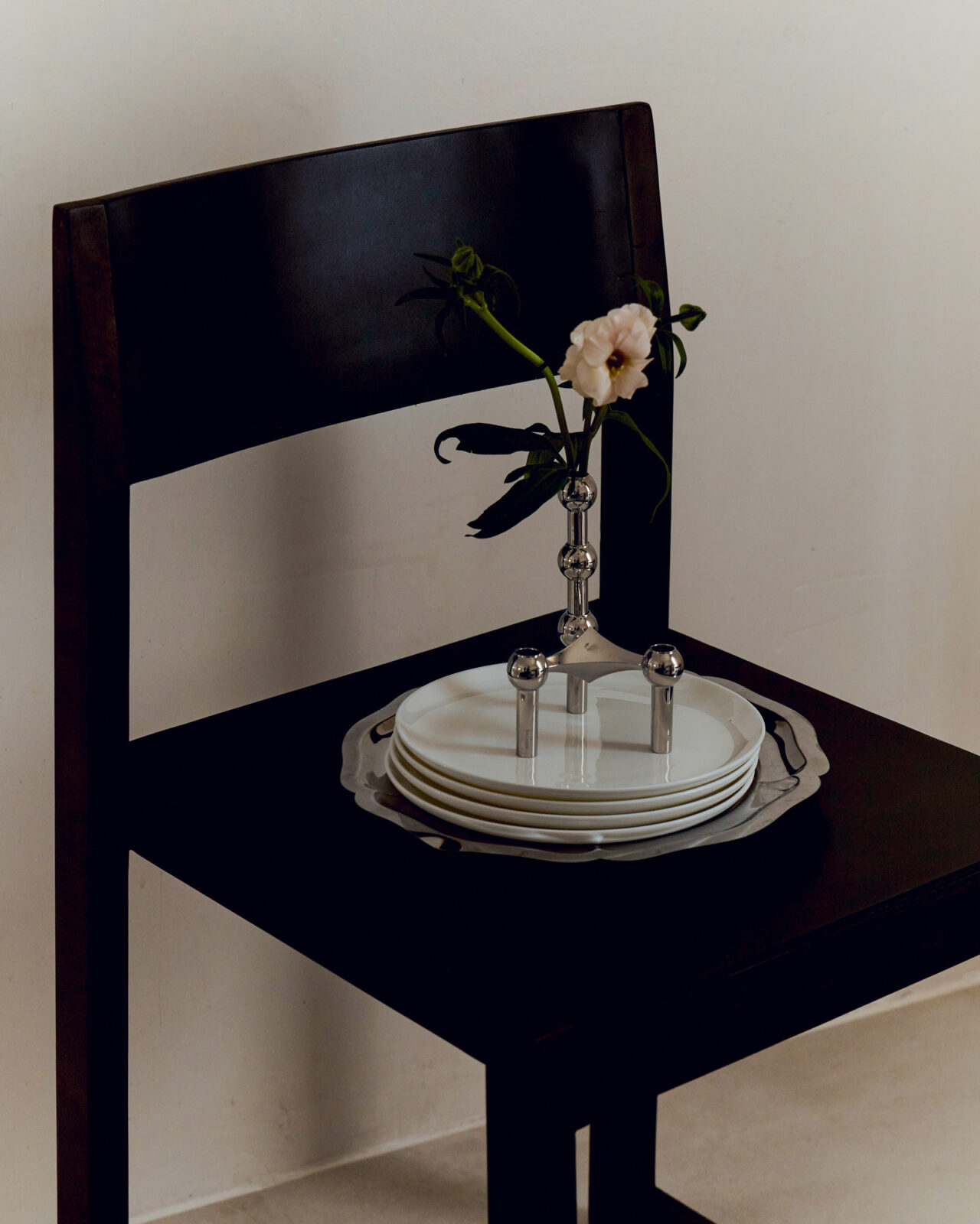 stoff nagel x claudia longarte. the nagel candle holder and vaser in chrome on a chair