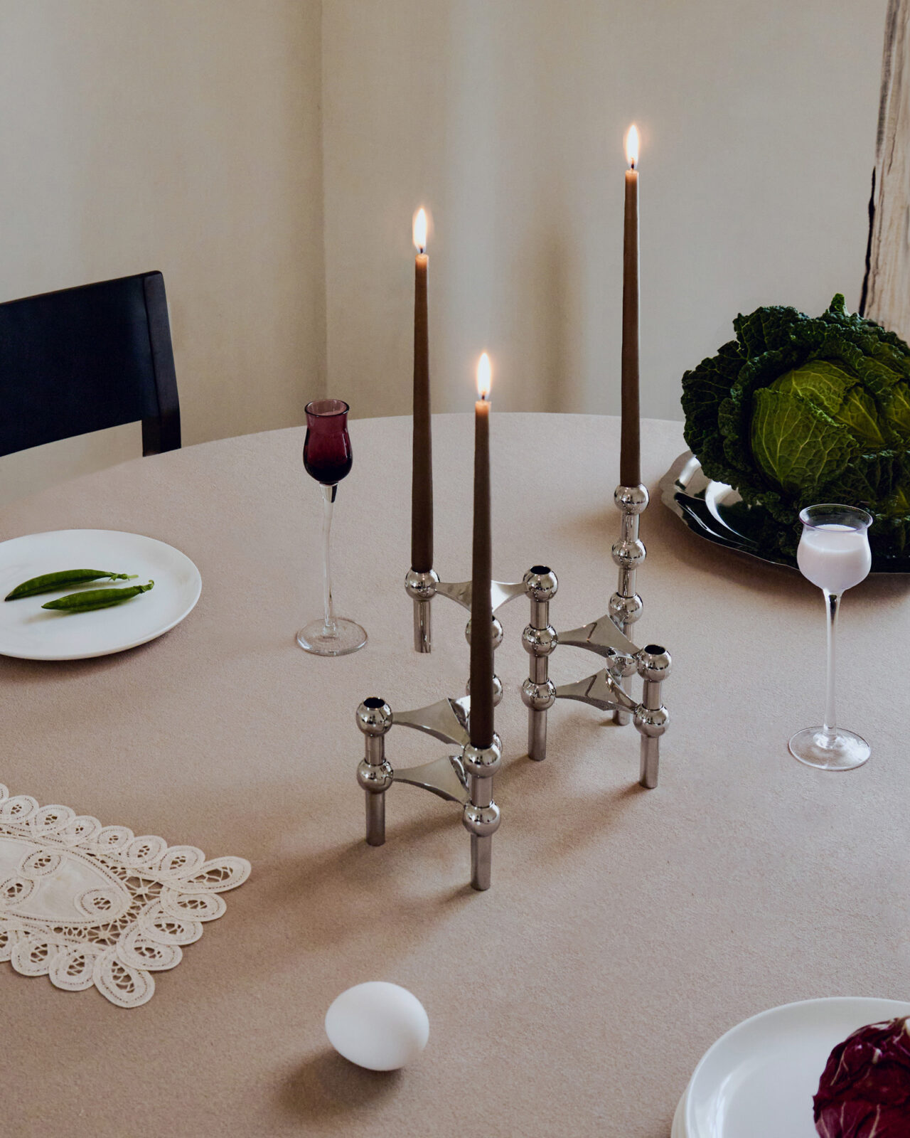 stoff nagel x claudia longarte. nagel candle holders in chrome arranged on a table with three lit candles