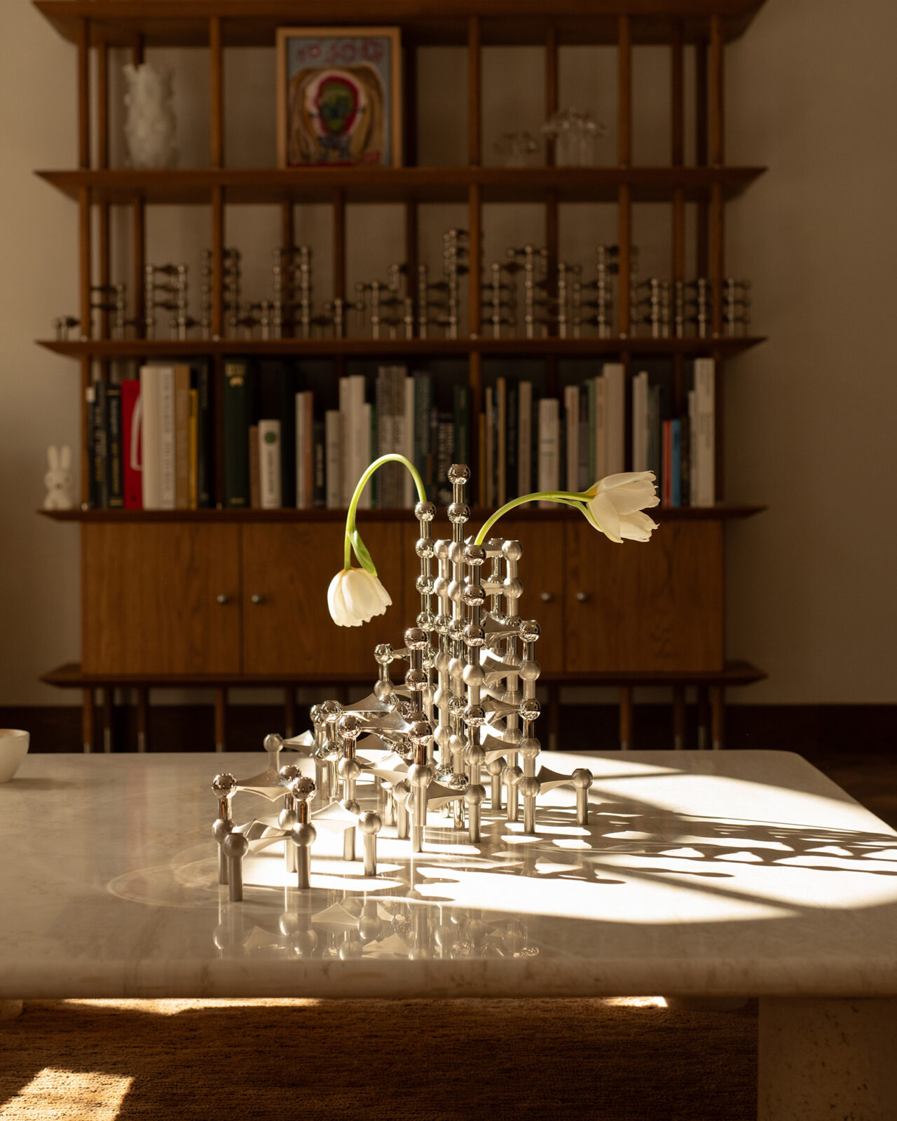 a summer styling by bonnie barlag for stoff nagel featuring a large candle holder sculpture of the nagel candle holder in brushed chrome and shiny chrome